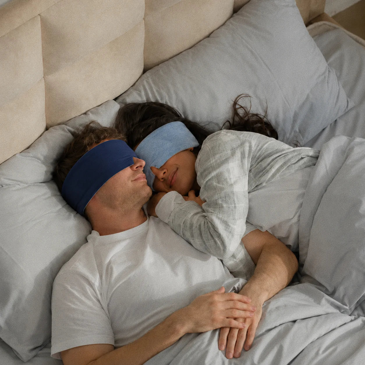 Two Navy Mellooa weighted sleep masks worn by a resting couple