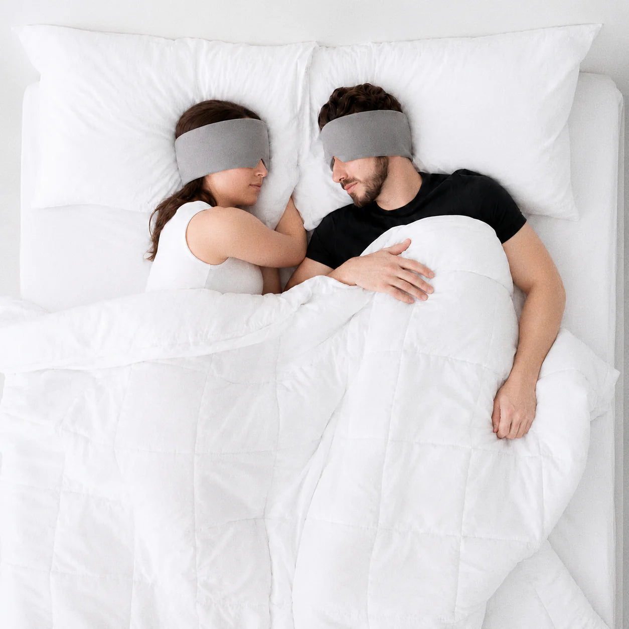 Two Warm Gray Mellooa weighted sleep masks worn by a resting couple